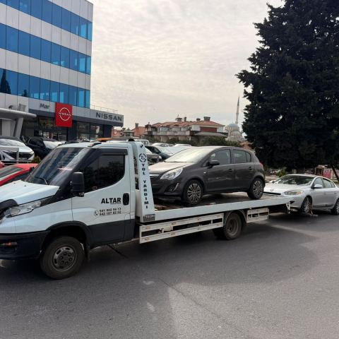 Beyaz sedan otomobil kayar kasa çekici platformunda şehir trafiğinde