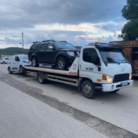 Koyu renk SUV oto çekici platformunda benzinlik önünde