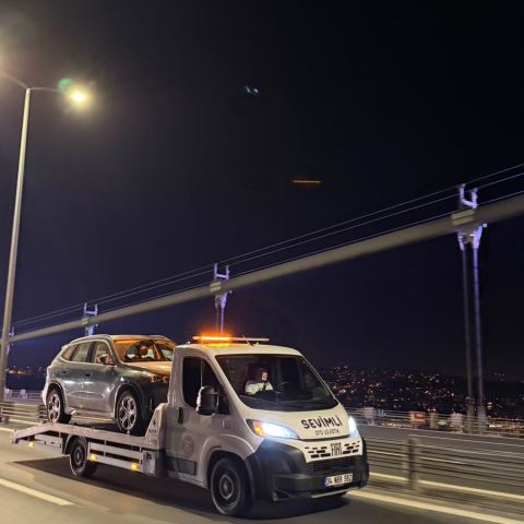 İstanbul gece manzarasında köprü üzerinde çekici ile araç taşıma