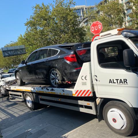 Altar logolu çekici siyah sedan aracı cadde üzerinde taşıyor